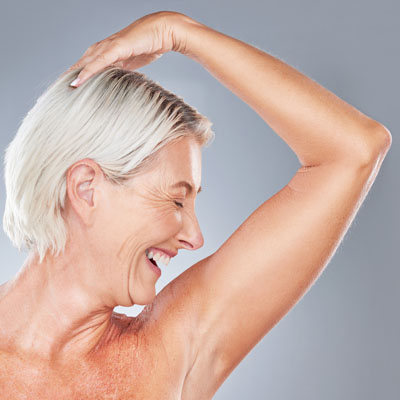 A smiling woman, representing the results of arm lift surgery in Dallas, Texas